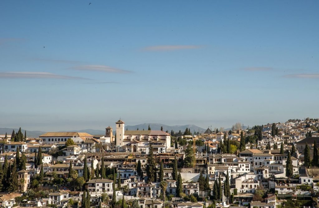 Panoramic view of a historic town with a prominent church tower under clear blue skies.