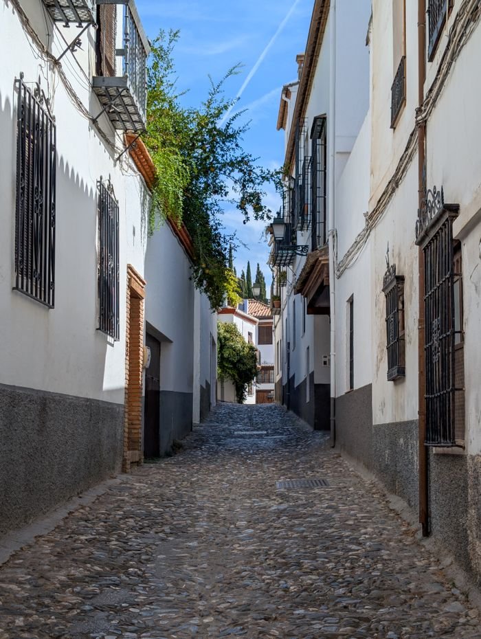 Discover a picturesque cobblestone street in Granada, showcasing traditional Andalusian architecture.